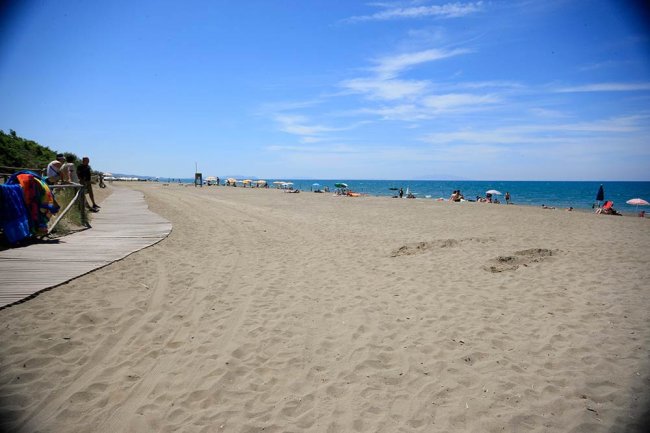 Spiaggia ampia e sabbiosa con mare blu.
