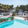 Complesso con piscina su una scogliera, circondato da vegetazione lussureggiante.
