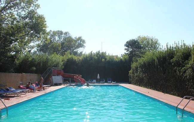 Piscina all'aperto con scivolo rosso.