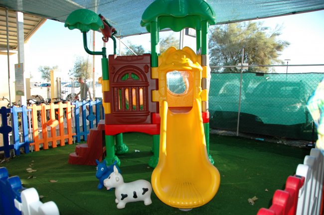 Un parco giochi colorato con uno scivolo giallo e giochi per bambini.