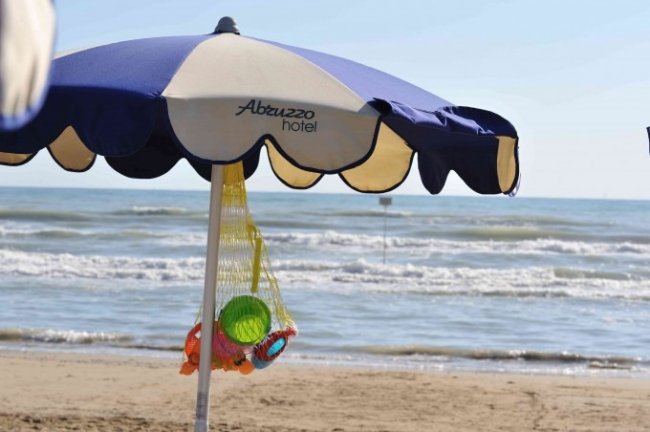 Ombrellone su spiaggia con mare sullo sfondo.
