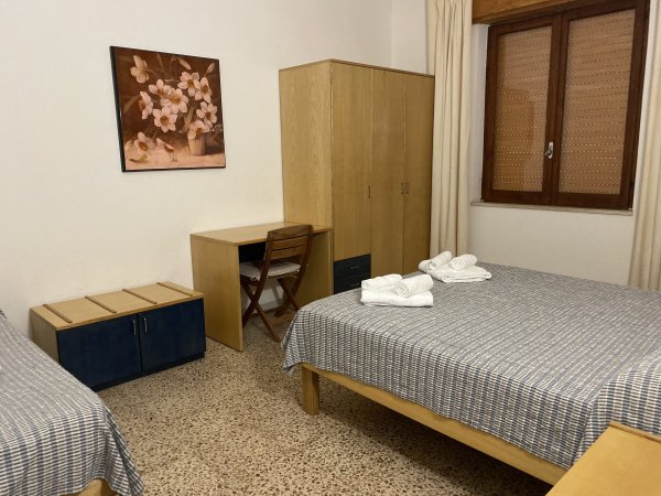 Camera con due letti, armadio e scrivania.