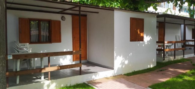 Casetta bianca con persiane marroni.