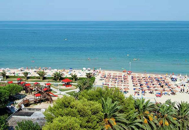 Spiaggia affollata con ombrelloni colorati e mare azzurro.