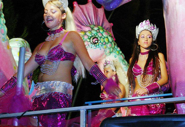 Persone in costumi colorati su un carro festivo.
