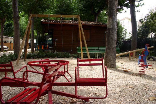 Area gioco con altalene e giochi a molla in un parco.