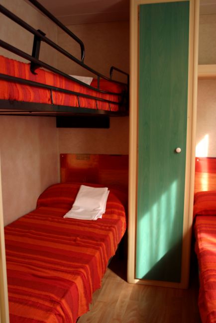 Letti a castello con coperte rosse in una stanza compatta.