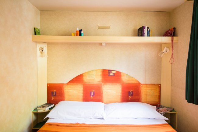 Letto matrimoniale con testata colorata.