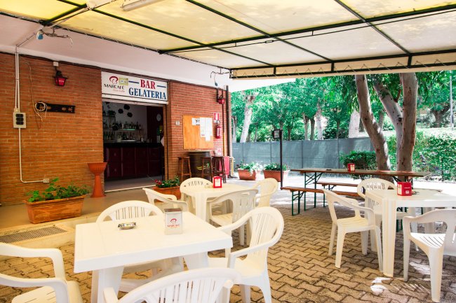 Bar all'aperto con tavolini bianchi.