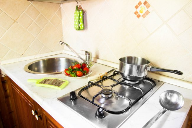 Cucina con fornello, lavello e utensili.