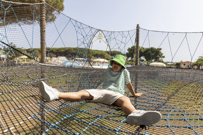 Bambino su rete da arrampicata con cappello verde.