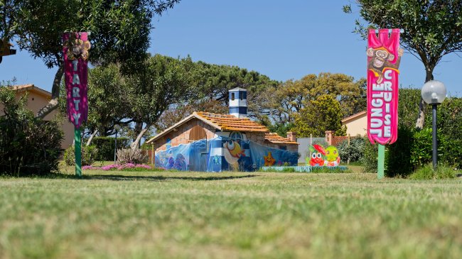 Casa colorata in un parco con due cartelli decorati.