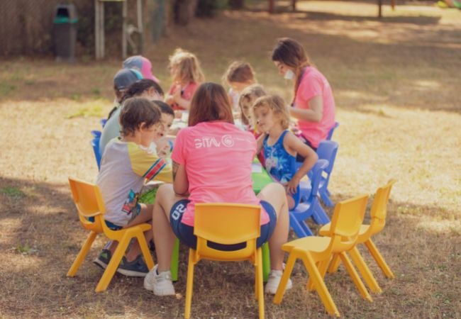 Bambini seduti a tavolino all'aperto per attività.