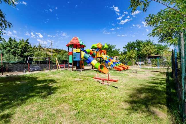 Parco giochi colorato con scivoli e altalene su un prato.
