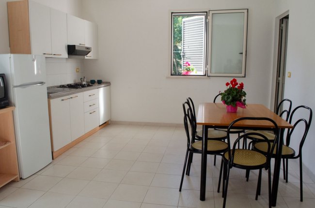 Cucina con tavolo da pranzo e sedie, finestra aperta.