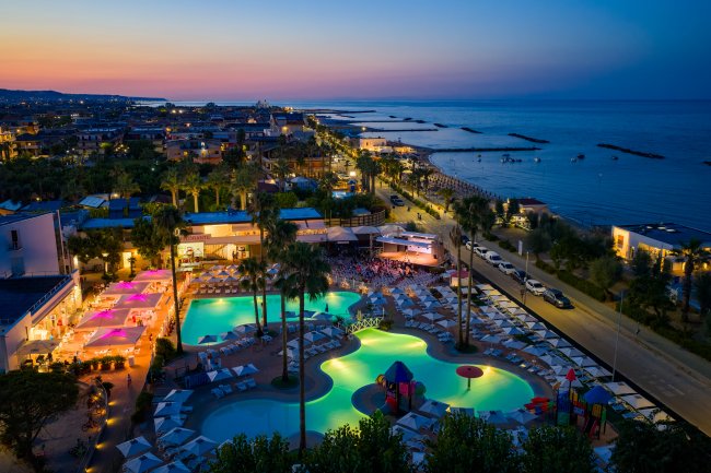 Piscina notturna illuminata con vista mare.