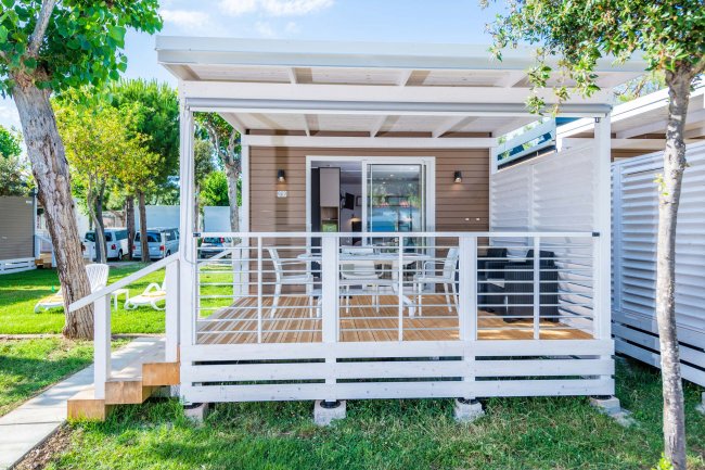 Veranda di una casa mobile bianca con tavolo e sedie.