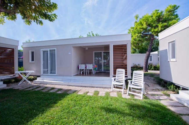 Bungalow moderno con veranda, sedie e tavolo.