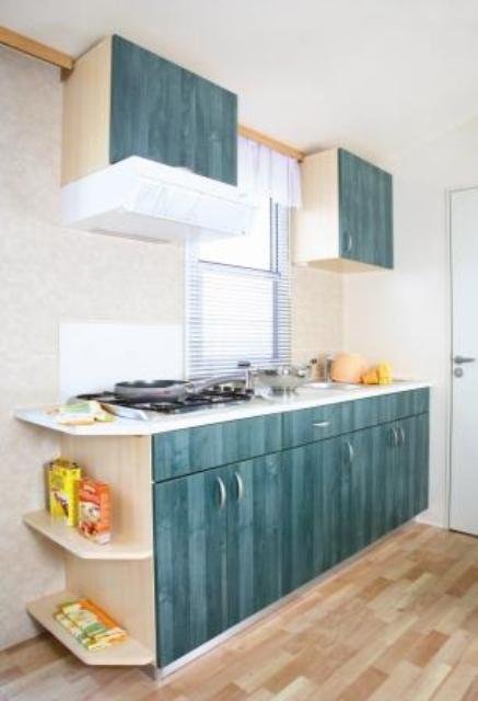 Cucina moderna con mobili verdi e pavimento in legno.