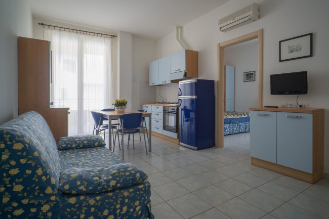 Soggiorno con cucina, divano blu a fiori gialli.