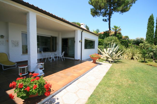 Veranda di una casa con giardino e arredi bianchi.