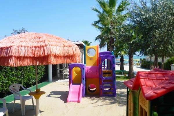 Area giochi con scivolo colorato in spiaggia.