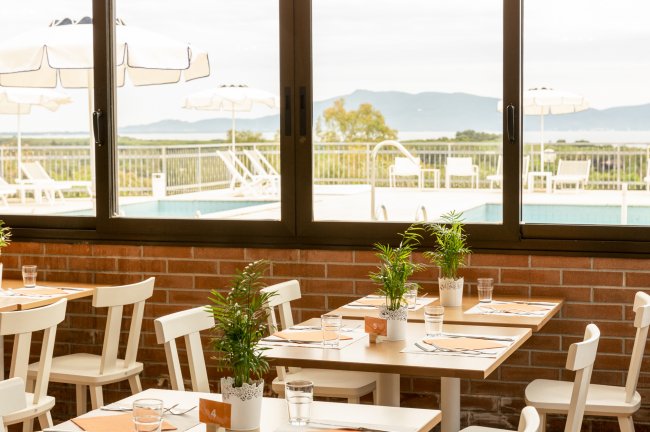Sala da pranzo con vista su piscina e montagne sullo sfondo.