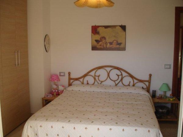 Camera da letto con letto matrimoniale, comodini e un quadro sopra la testata.