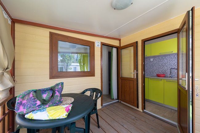 Veranda con tavolo nero e accesso cucina.