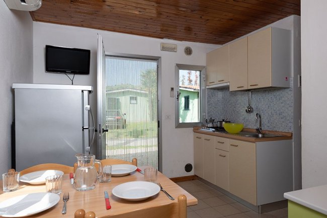 Cucina con tavolo da pranzo, frigo e porta aperta.