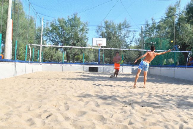 Due persone giocano a beach volley in un campo sabbioso.