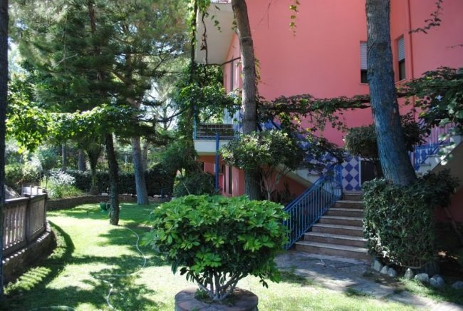 Giardino verde con casa rosa e scala.
