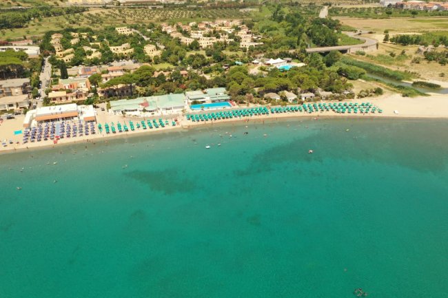 Spiaggia con mare turchese e strutture turistiche.