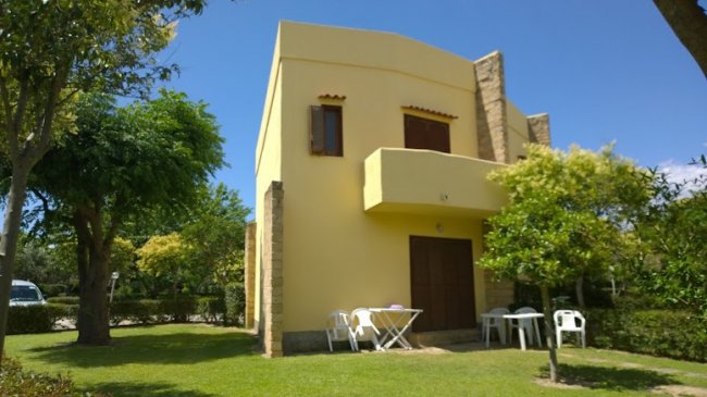 Casa gialla a due piani con balcone e giardino.
