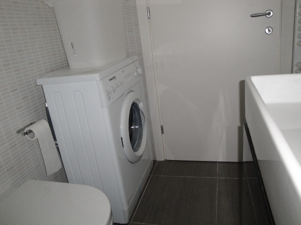 Bagno con lavatrice bianca e mobile con lavabo.