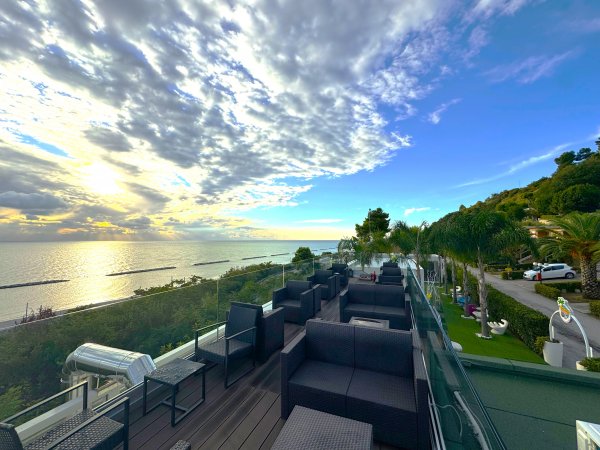 Terrazza con sedie, vista sul mare e cielo nuvoloso.