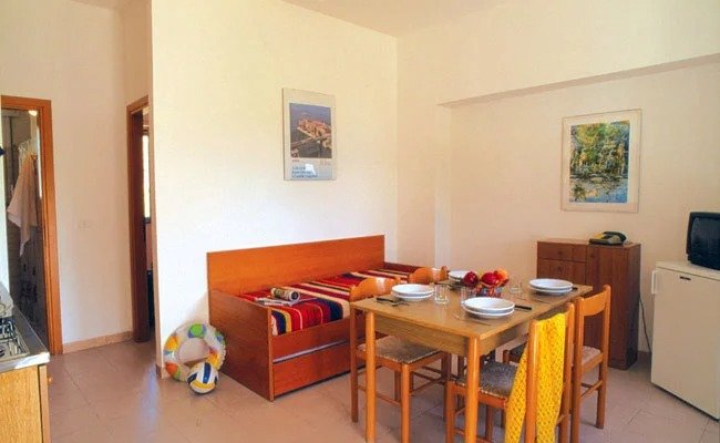 Soggiorno con tavolo apparecchiato, letto singolo e pareti colorate.